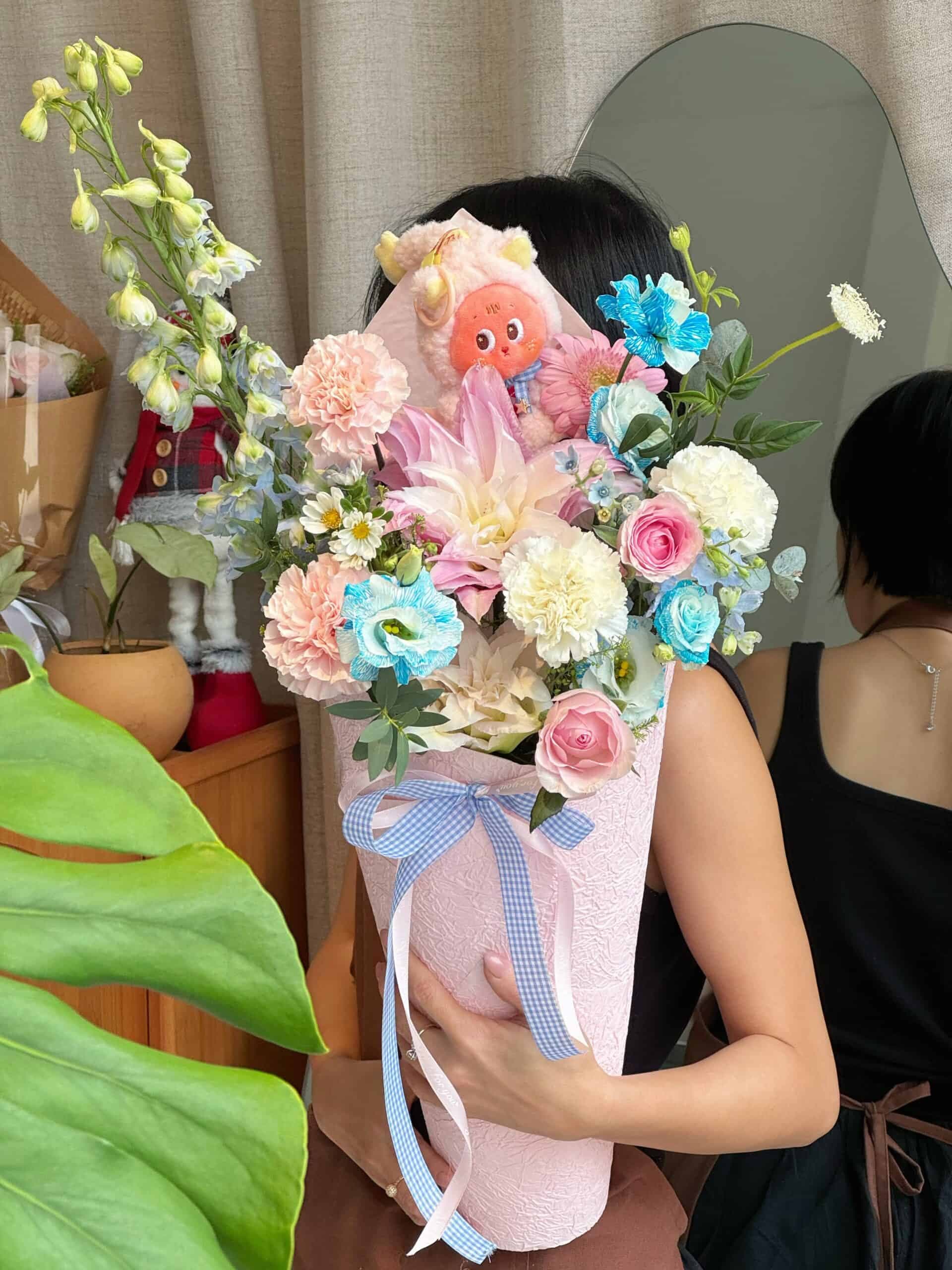 Bó hoa tươi đẹp với nhiều loại hoa màu pastel và đồ chơi thú nhồi bông.